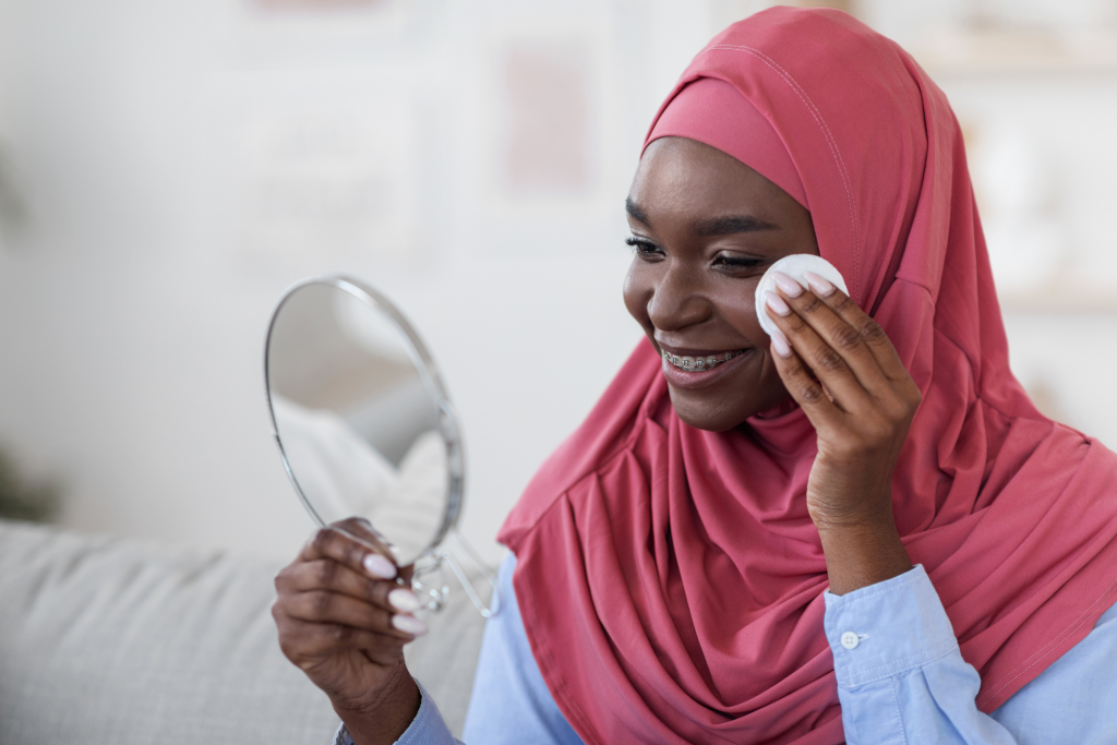 young woman wearing hijab applying sulfur spot treatment for acne