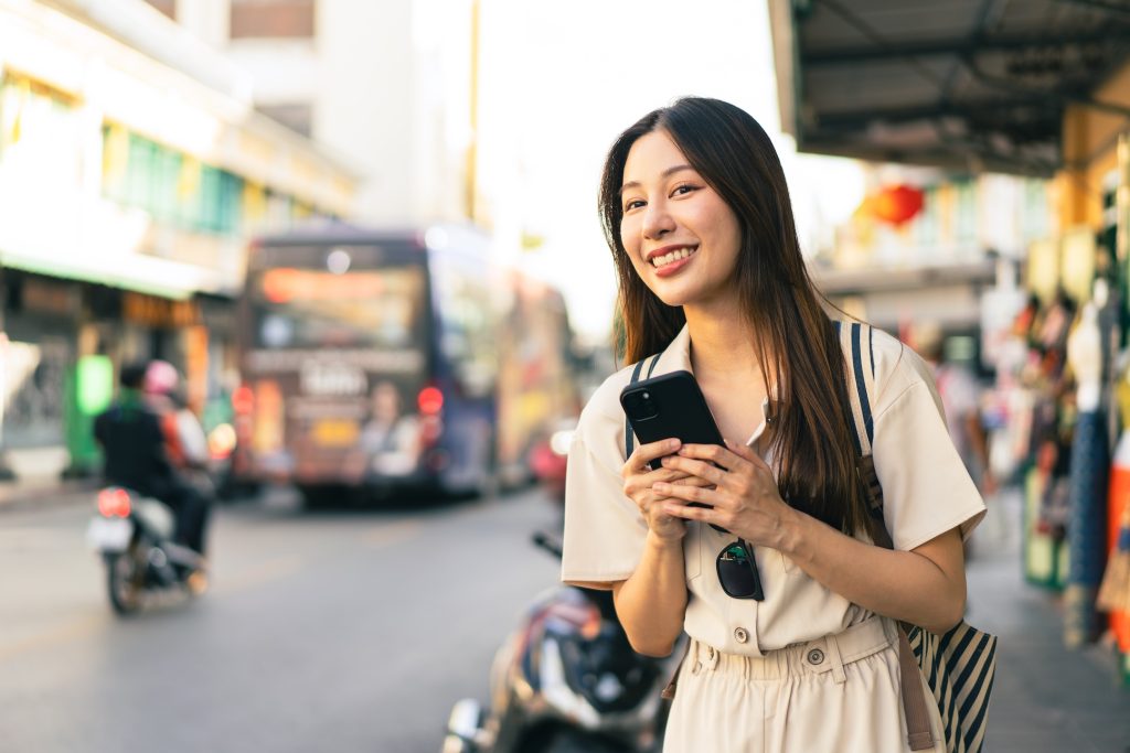 smiling woman using taxi ap while traveling