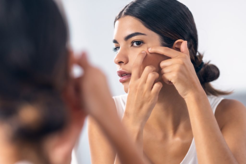 woman removing pimple from her face