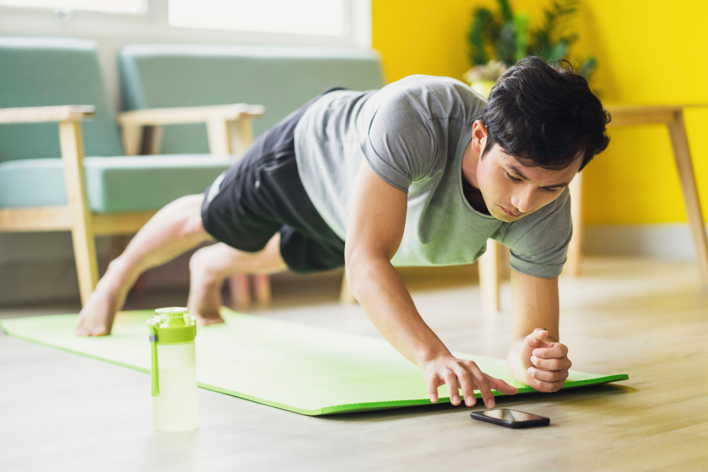 young man doing yoga exercises using self-care apps on his phone